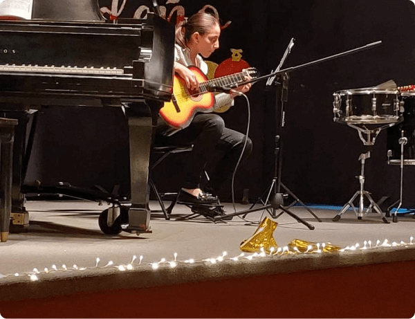 Niña tocando la guitarra en un recital de música